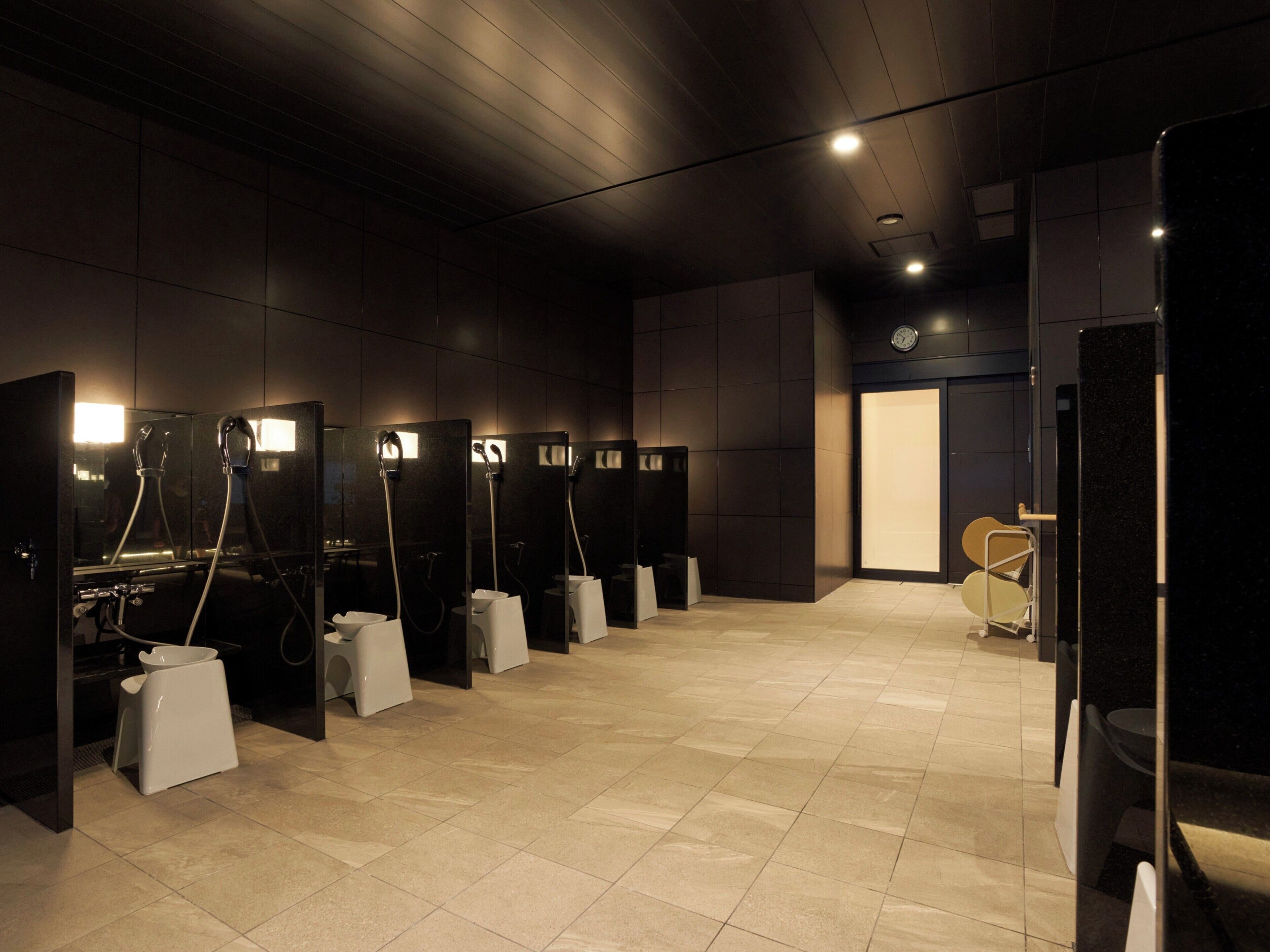 Een moderne toiletruimte met meerdere cabines, elk voorzien van een spiegel en een handdroger.