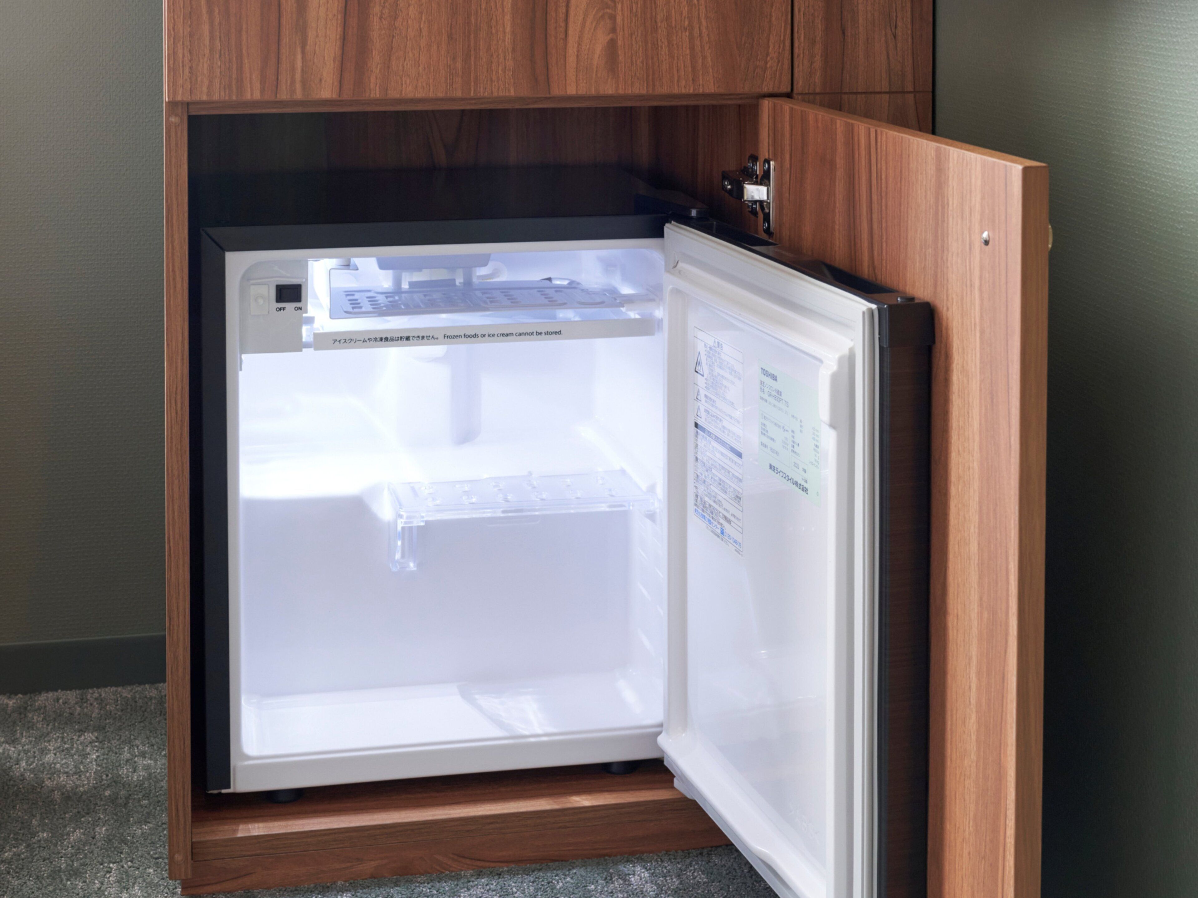 A refrigerator with a wooden cabinet above it.