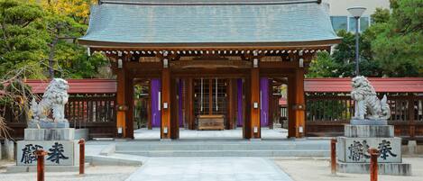 A traditional Japanese building with a tiled roof, wooden pillars, and two lion statues at the entrance.