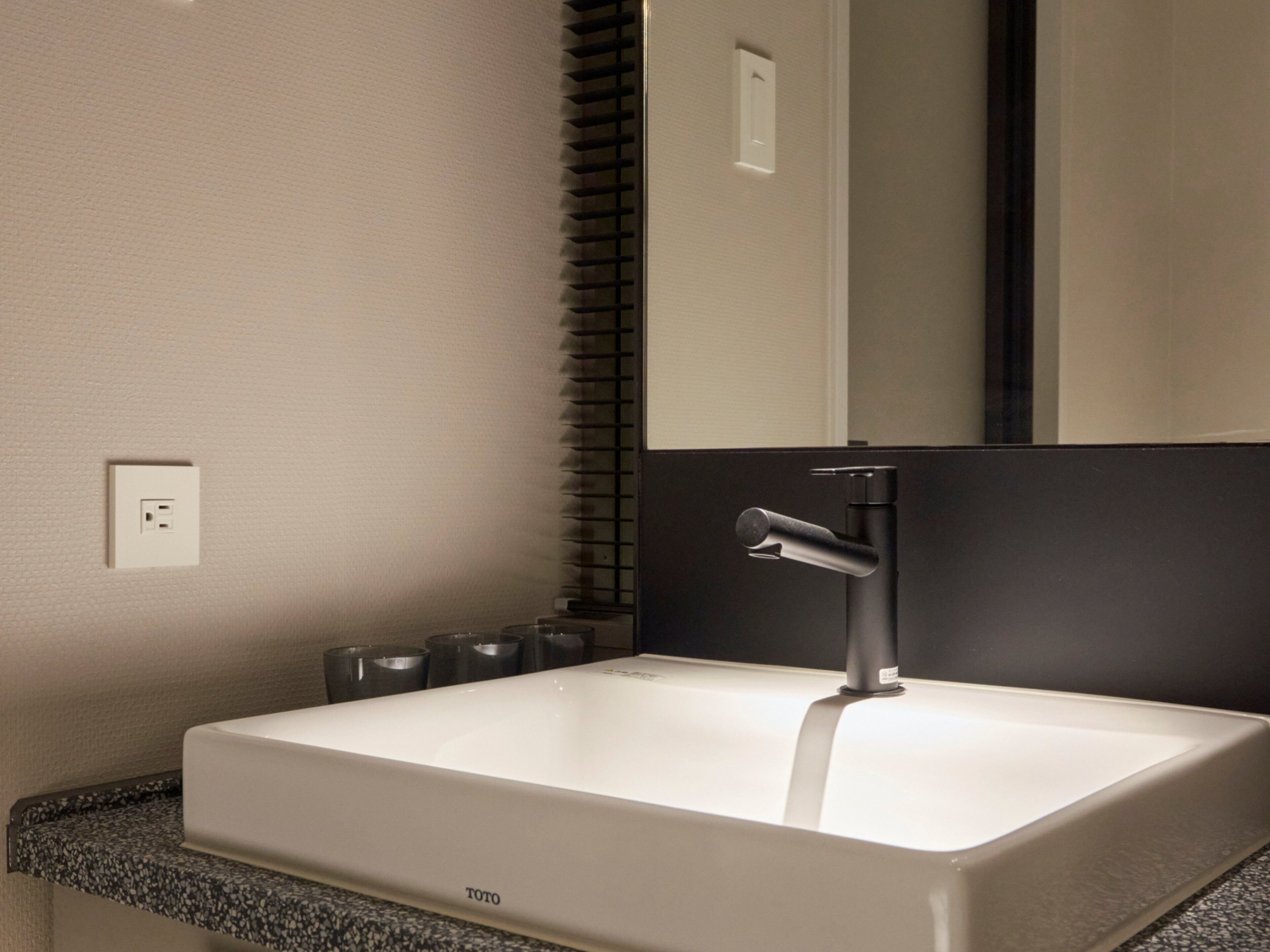 A modern bathroom with a white sink, black faucet, and a mirror above it.