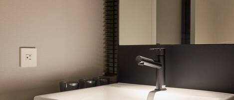 A modern bathroom with a white sink, black faucet, and a mirror above it.