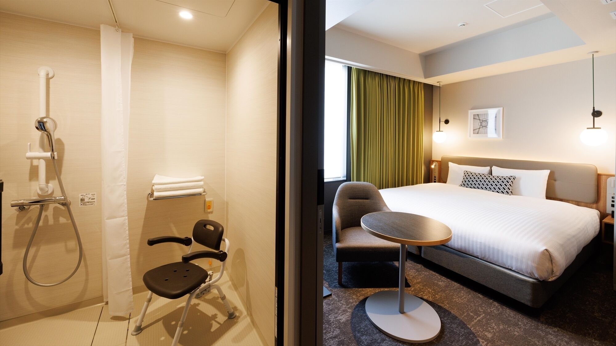 A hotel room with a bed, a chair, a small table, a shower, and a window with curtains.