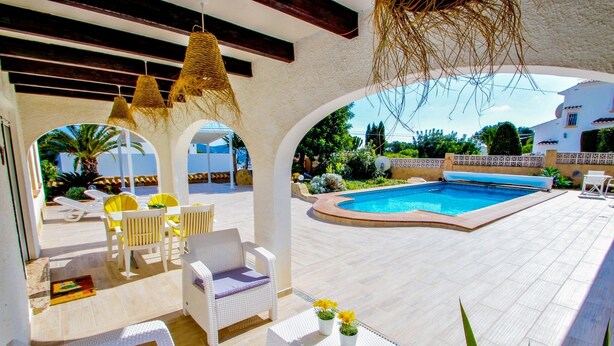 An outdoor pool area with white wicker furniture, a pool, and a view of the surrounding landscape. - La Tranquilidad - private pool villa with panoramic views in Moraira (Teluda)