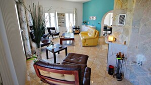 A spacious living room with a yellow sofa, brown leather chairs, and a stone accent wall. - La Tranquilidad - private pool villa with panoramic views in Moraira (Teluda)
