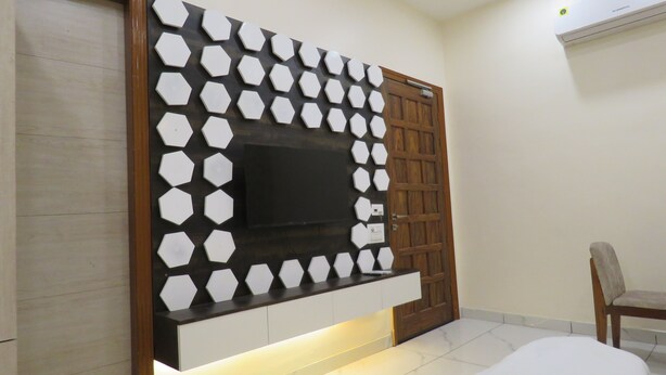 Un salon moderne doté d’un grand téléviseur à écran plat fixé au mur, lequel est décoré d’un motif géométrique.