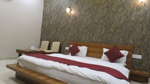 A bedroom with a bed, two bedside tables, a nightstand, and a wall with a leaf pattern.