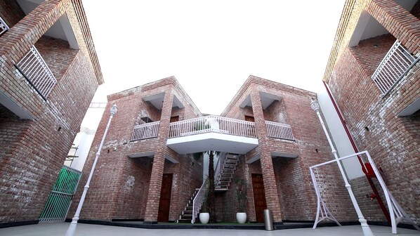 A building with a symmetrical facade, featuring a central balcony with white railings and a staircase leading to an upper level.