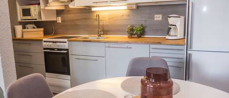 Een koelkast, een magnetron, een vaatwasser, kookgerei, borden en bestek