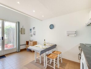 A modern kitchen with white cabinets, a dining table set for four, and a clock on the wall.