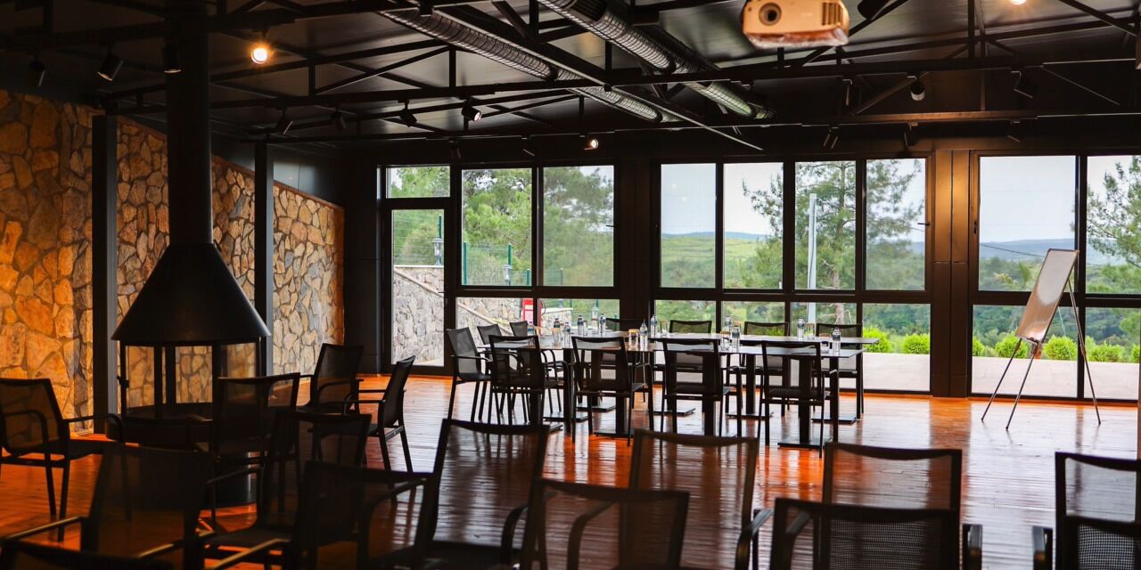 Un restaurante con paredes de piedra, ventanas amplias y vistas al exterior.