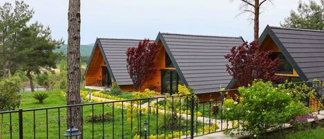 Filas de cabañas modernas con techos triangulares y un jardín bien cuidado al frente.