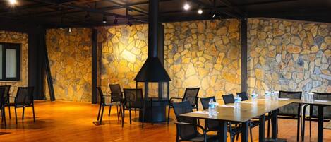 A conference room with a stone wall, a black chimney, wooden tables, and chairs.