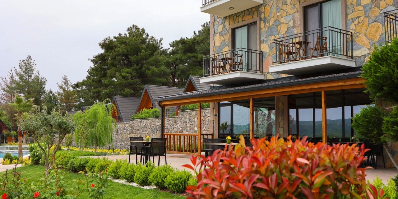 A stone building with a balcony, outdoor seating, and a garden.