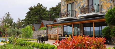 A stone building with a balcony, outdoor seating, and a garden.