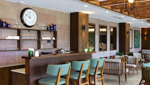 Um interior moderno com área de bar, assentos e um relógio na parede.
