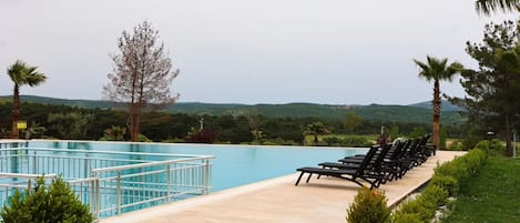 A swimming pool with lounge chairs and a view of hills.