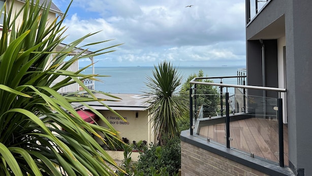 A balcony with a view of the sea, a reception area, and a bar & bistro sign.