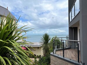 Un balcon avec vue sur la mer, un espace d’accueil et une enseigne indiquant la présence d’un bar-bistro.