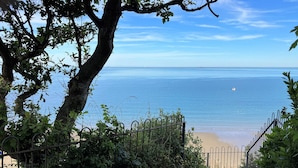 A pathway leading to a beach with a metal fence and greenery on the sides.