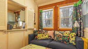 A cozy room with a dark-colored sofa, a small table, and a window with curtains.