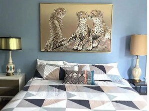 Cozy retreat with a large bed, nightstand, and wall art.