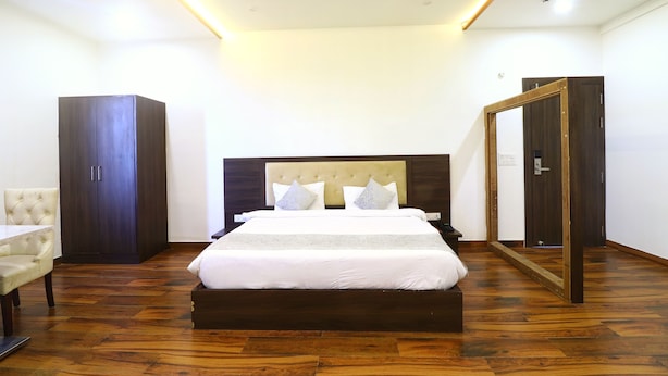 A bedroom with a large bed, a wardrobe, a desk, and a mirror. - Hotel Taj Venture By Park Tree (Agra)