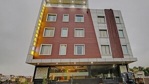 A multi-story hotel with a modern design, featuring a combination of red and white exterior walls, large windows, and a prominent vertical strip on the right side. - Hotel Taj Venture By Park Tree (Agra)