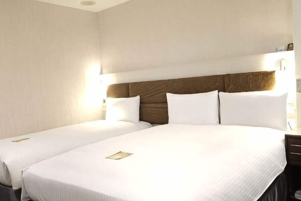 Une chambre d’hôtel avec deux lits, une tête de lit en bois et des lampes de chevet.