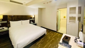 A hotel room with a large bed, a desk with a lamp, a phone, and a remote control. - Hub Hotel - Banqiao Station (New Taipei City)