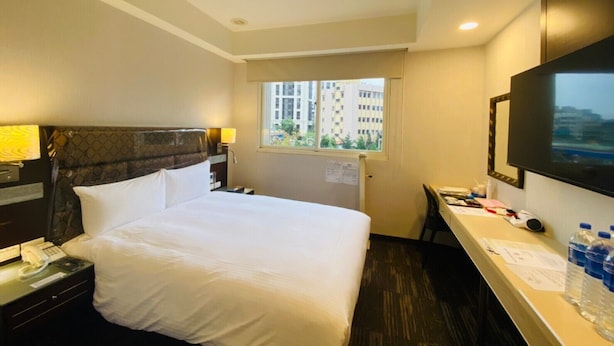 A hotel room with a bed, bedside table, lamp, window, desk, chair, and a flat-screen TV. - Hub Hotel - Banqiao Station (New Taipei City)