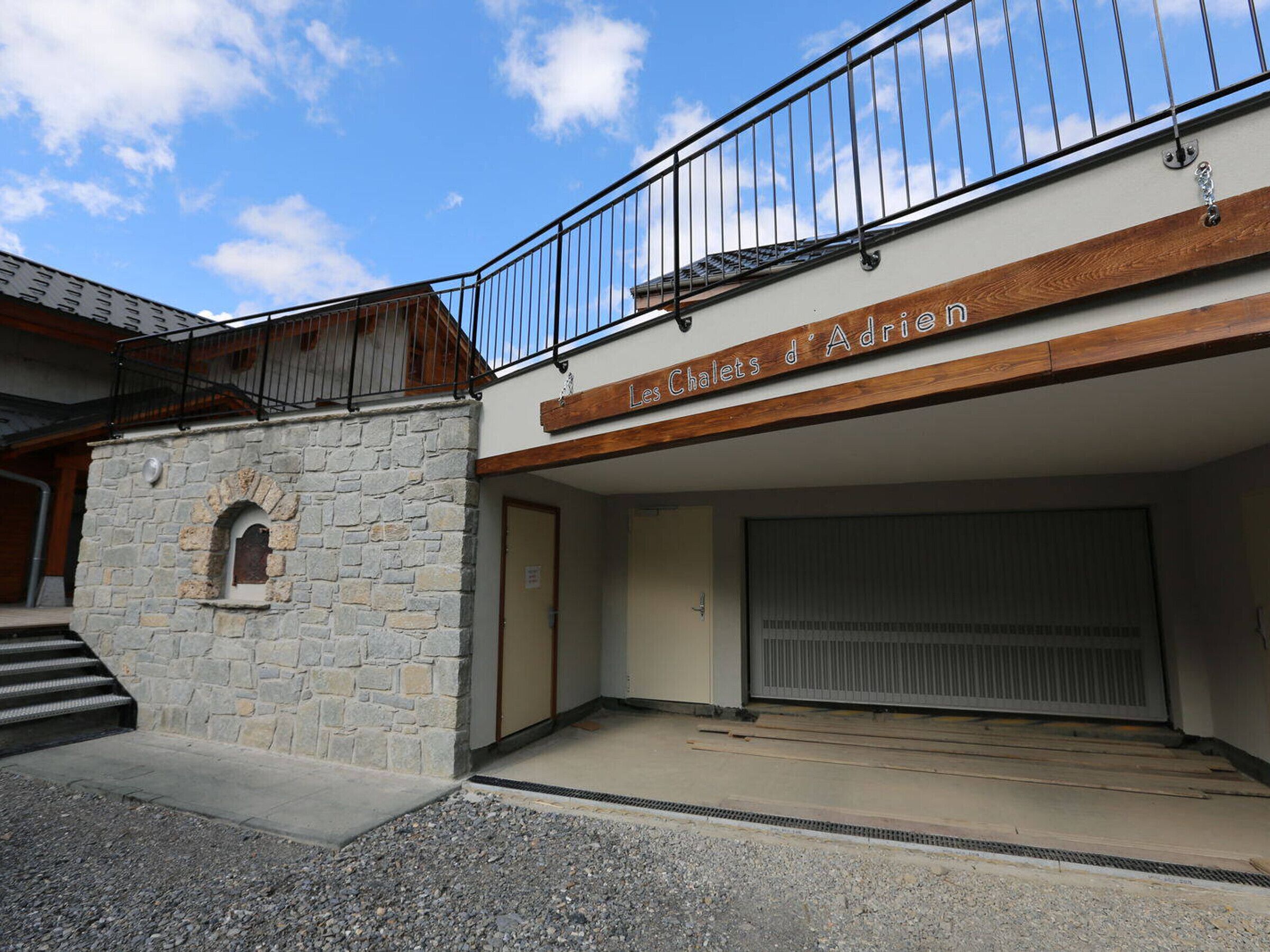 A building with a stone facade, a wooden upper floor, and a sign reading "Les Chalets d'Adria".