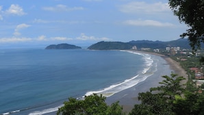 A coastal view with a beach, ocean, and distant hills.
