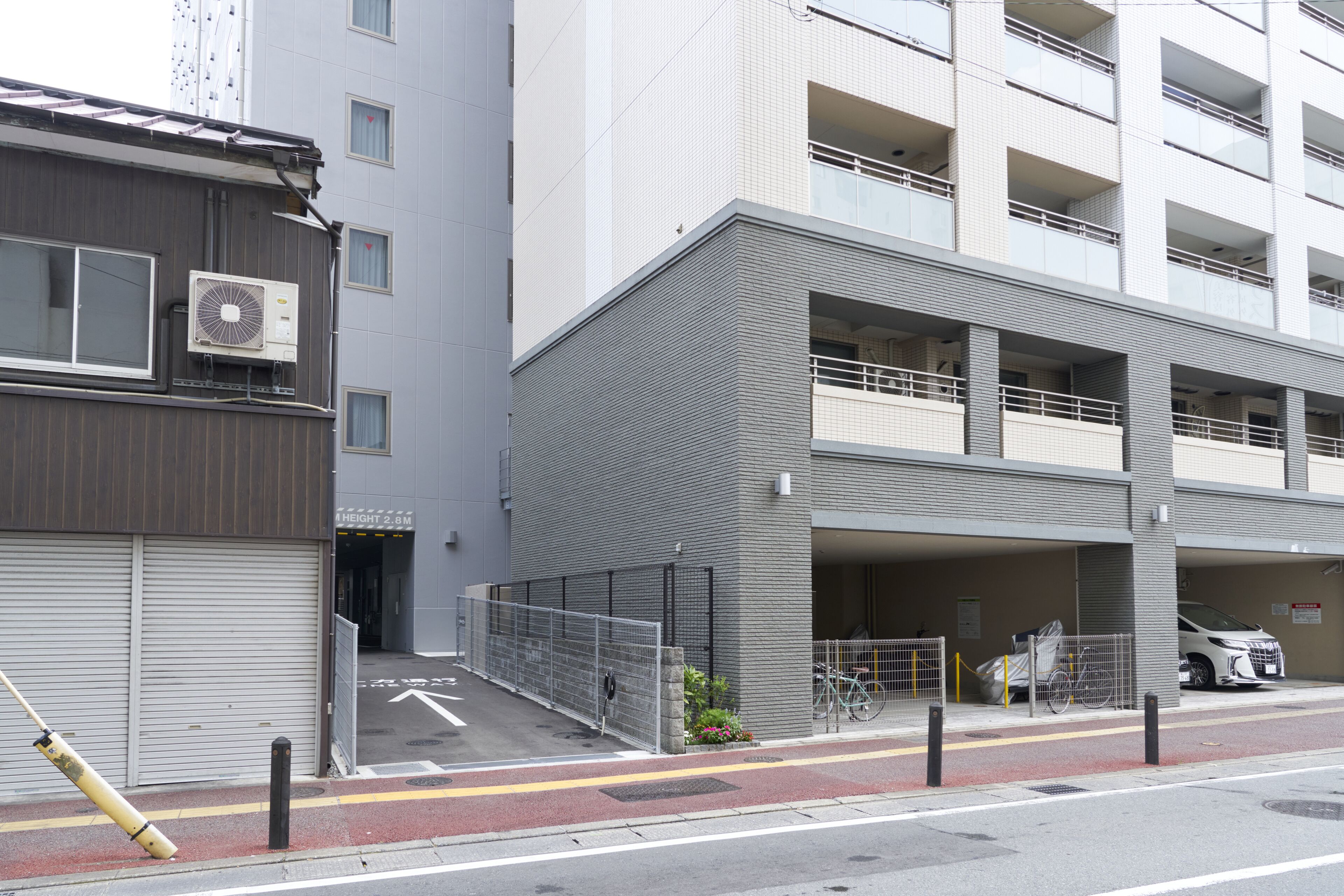 A multi-story parking garage with a covered entrance, a bicycle rack, and a white car parked inside.