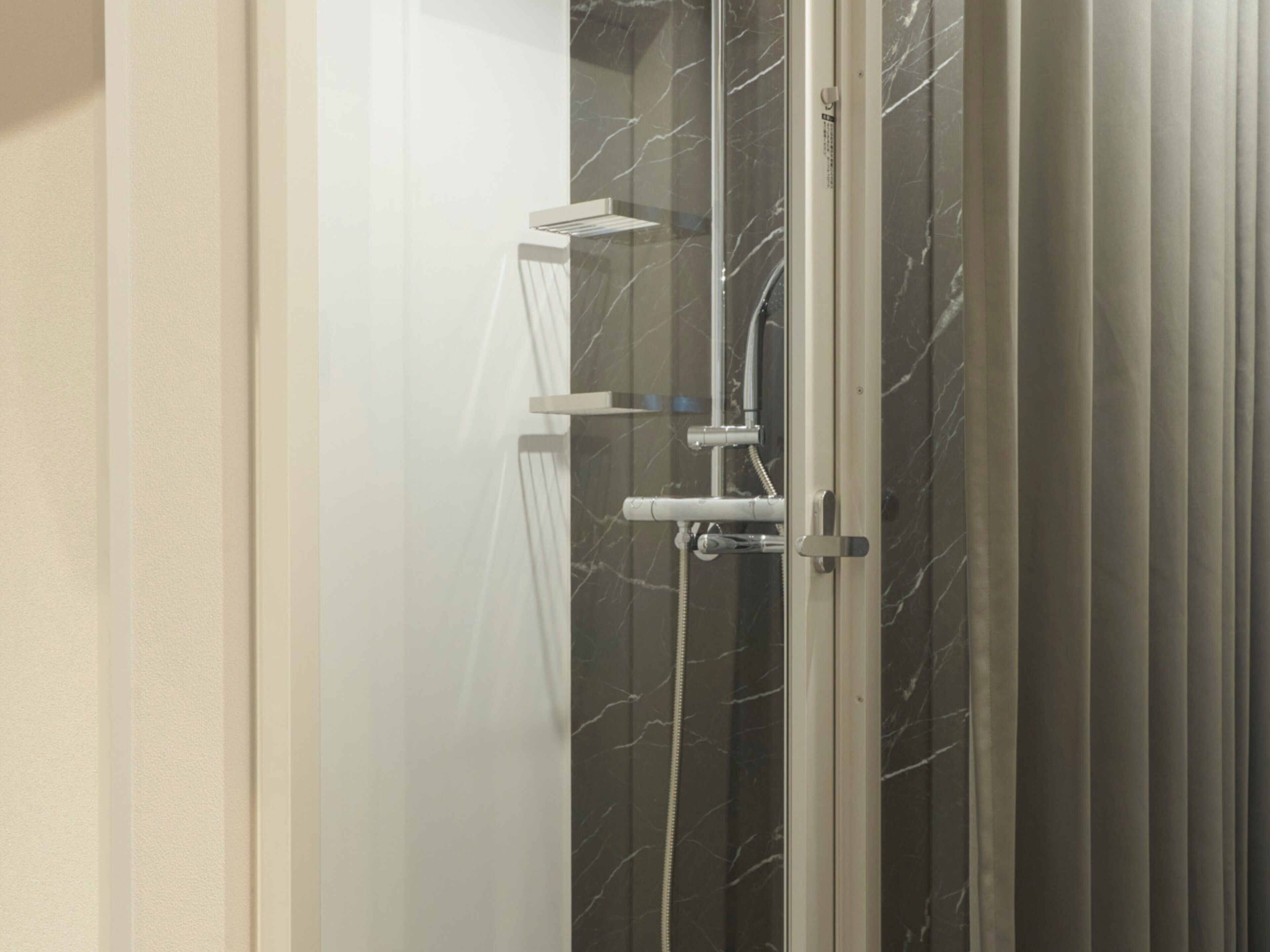 Une douche avec une porte en verre et un mur en marbre.