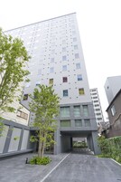 A modern building with a flat facade, multiple windows, and a covered entrance area.