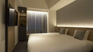 A modern hotel room with a large bed, a wardrobe, a desk, and a view of a forest through a window.