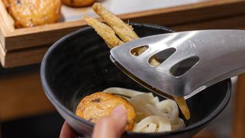 Un tazón de fideos con un trozo de comida frita y un tenedor.