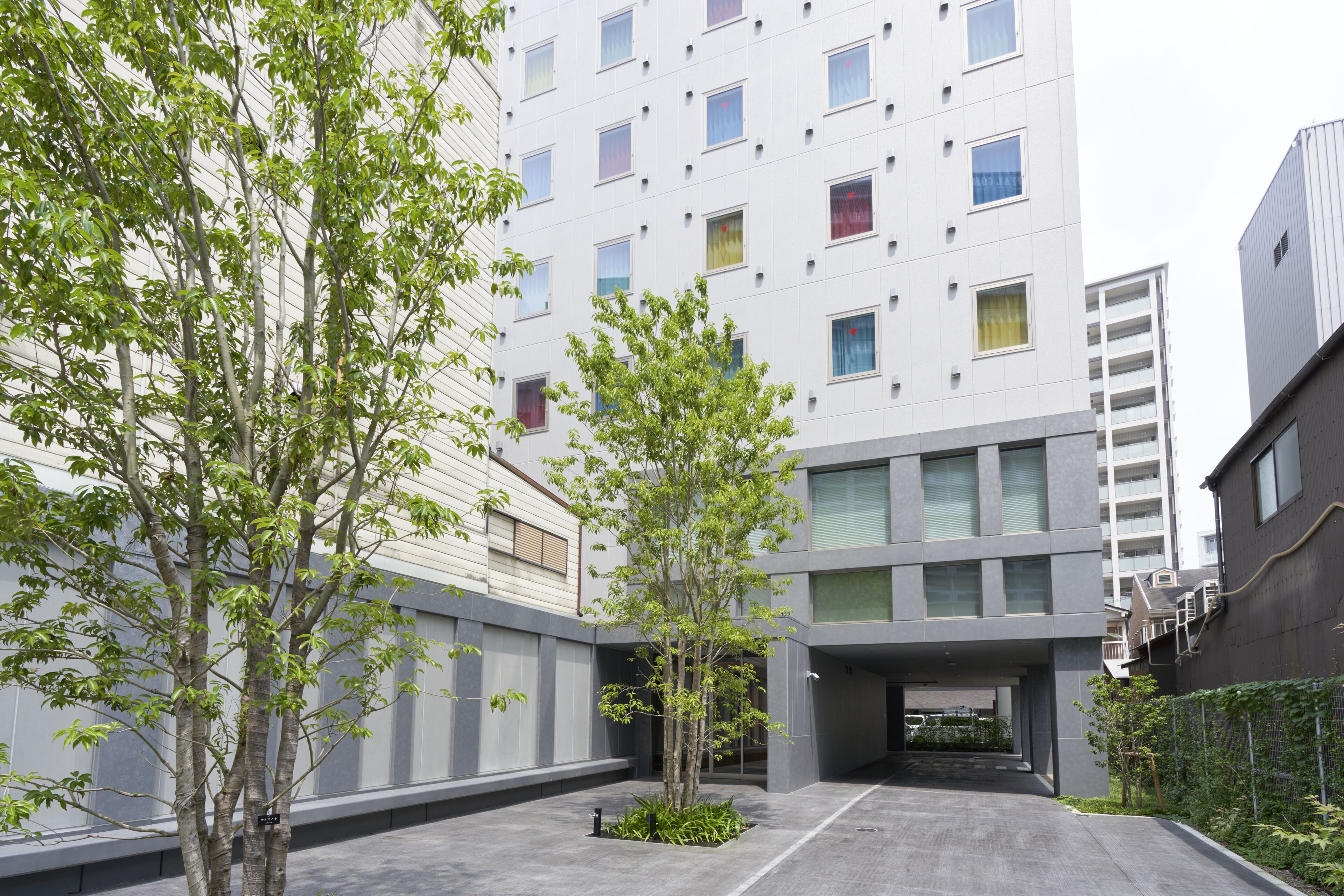 A modern building with a courtyard featuring trees and a covered walkway.