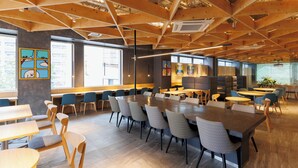 Une salle de conférence moderne avec des poutres en bois, de grandes fenêtres et différents types de sièges.