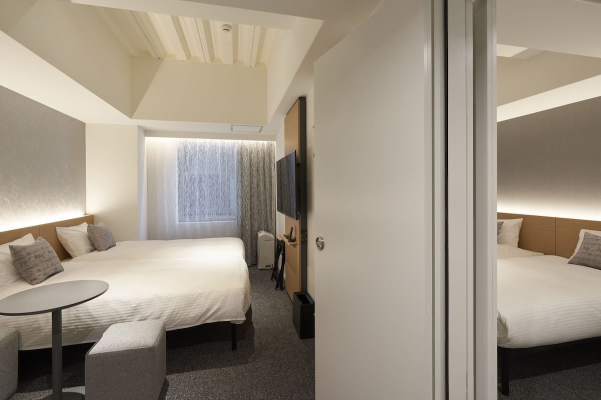 Une chambre d’hôtel avec deux lits, une petite table et un téléviseur.
