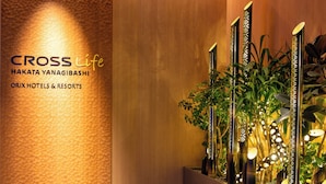 Un espace d’accueil doté d’un mur à texture, d’un panneau en bois et d’une présentation de plantes avec des vases verticaux.