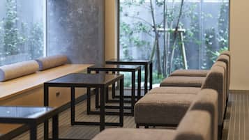 A modern interior with seating arrangements, tables, and a view of greenery outside.