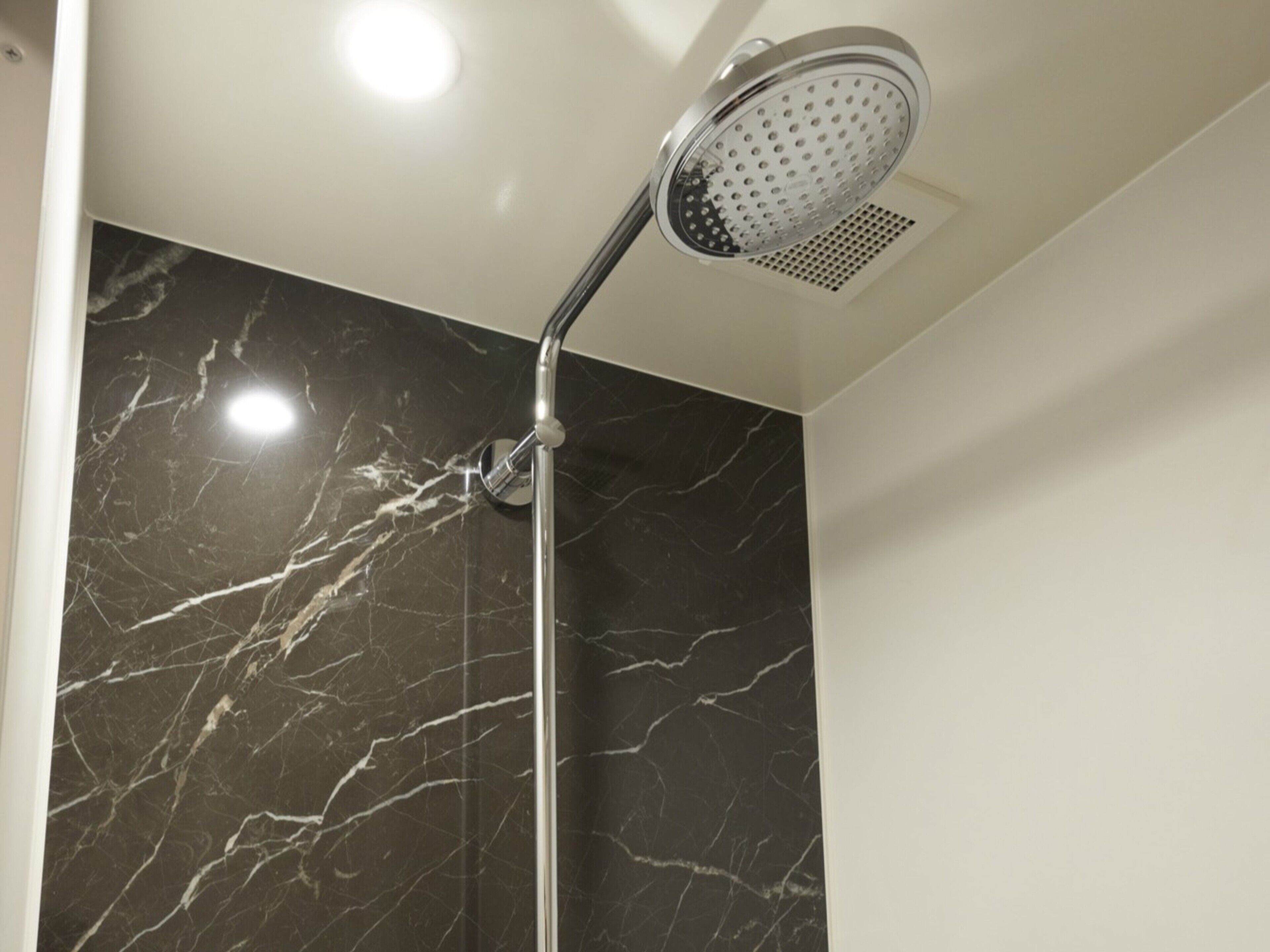 A shower with a modern design, featuring a chrome finish and a perforated showerhead.