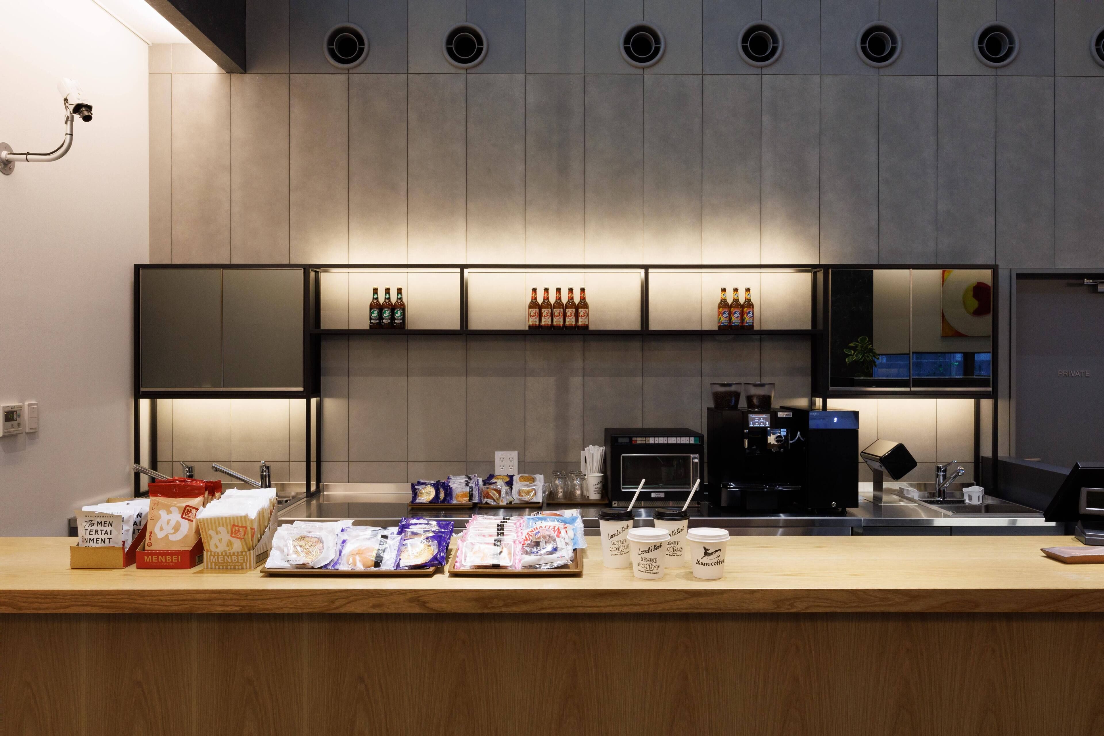 A modern bar area with shelves of beverages, a coffee machine, and packaged snacks.