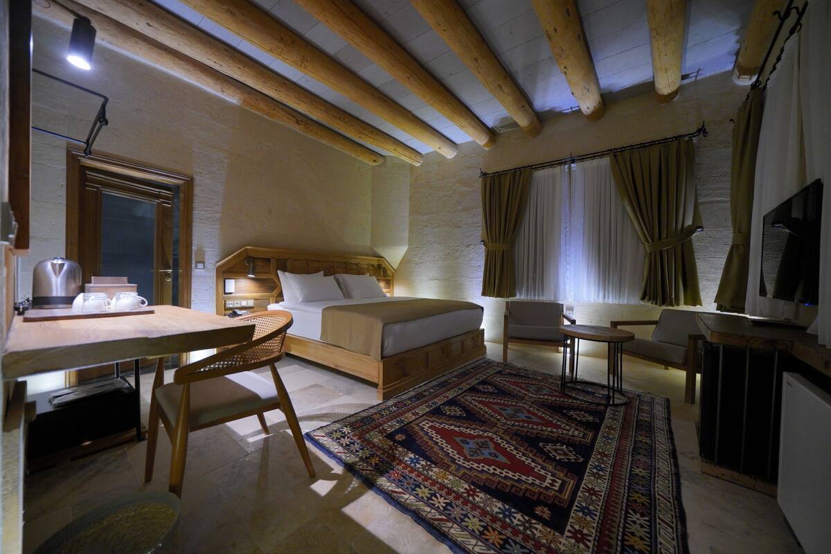 A cozy room with a bed, a desk, a chair, and a TV.