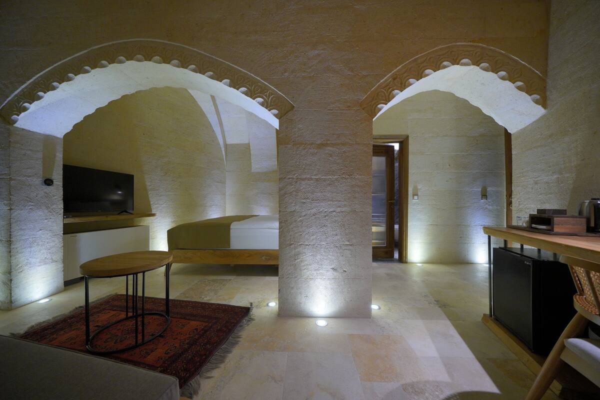 A spacious room with a high ceiling, stone columns, and a wooden desk with a chair.