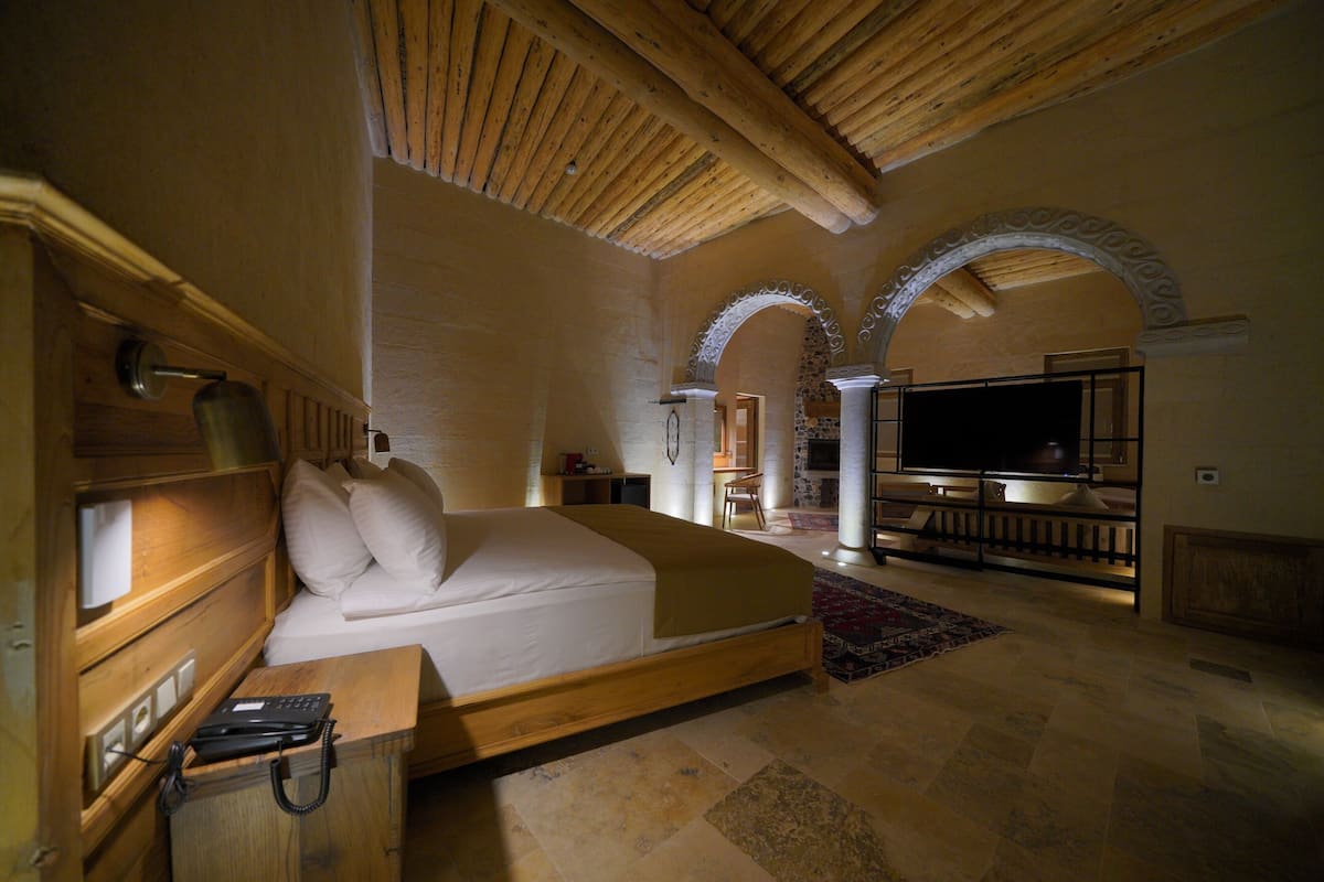 A spacious bedroom with a large bed, wooden headboard, and a television.