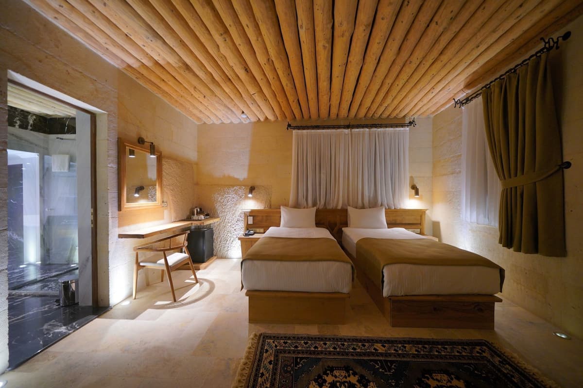 A room with two beds, a desk, a chair, a mirror, a small table, and a rug.