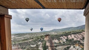 A hot tub with a view of a mountainous landscape and hot air balloons. - Kappadoks Cave Hotel (Nevsehir)