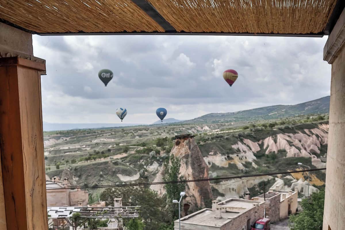 A hot tub with a view of a mountainous landscape and hot air balloons.